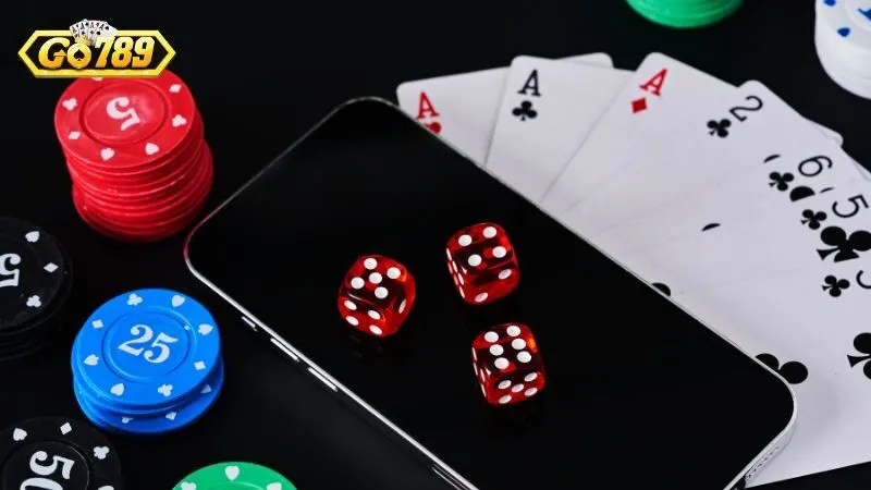 Chip casino, xúc xắc đỏ và bộ bài đặt cạnh điện thoại có logo GO789